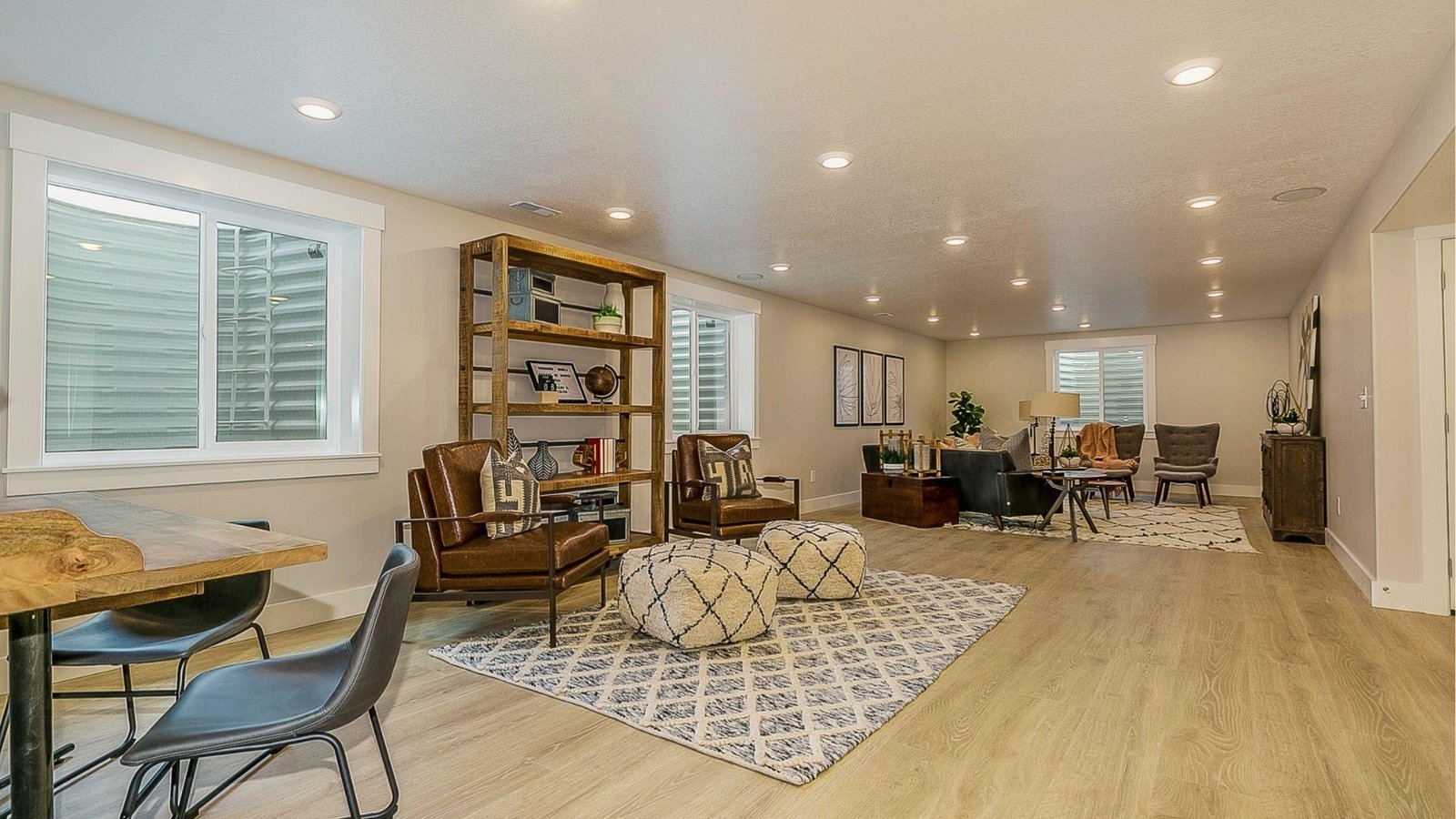 Spacious finished basement family room with leather chairs and rugs demonstrating mid-range basement renovation cost investment.