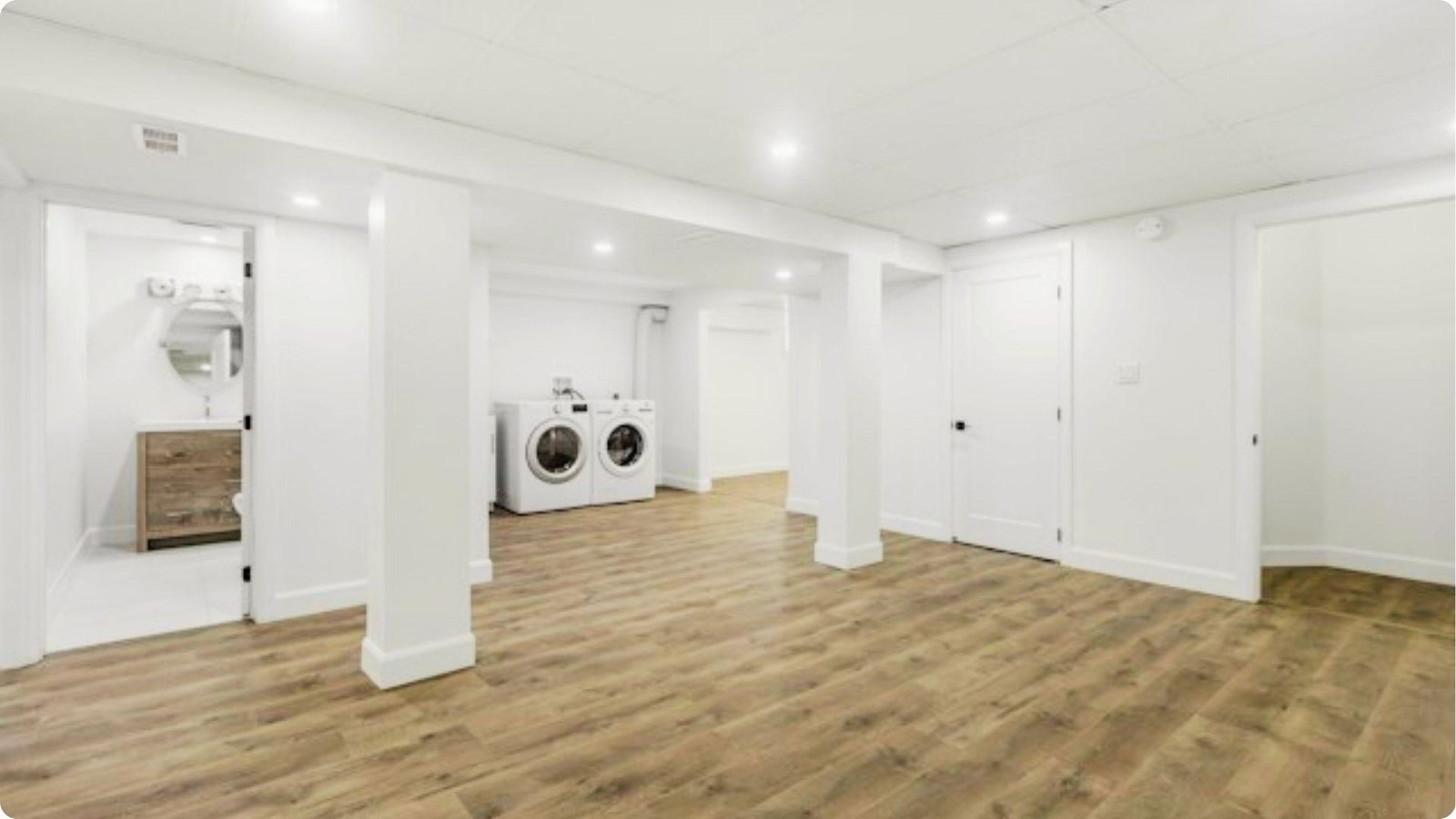 Bright, modern basement renovation with wood-look flooring and white walls.