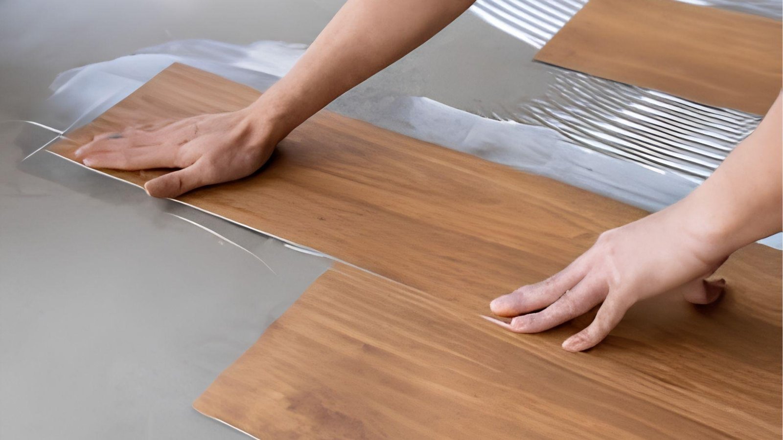Contractor installing wood-look vinyl flooring in basement remodel to control basement renovation cost while improving durability.