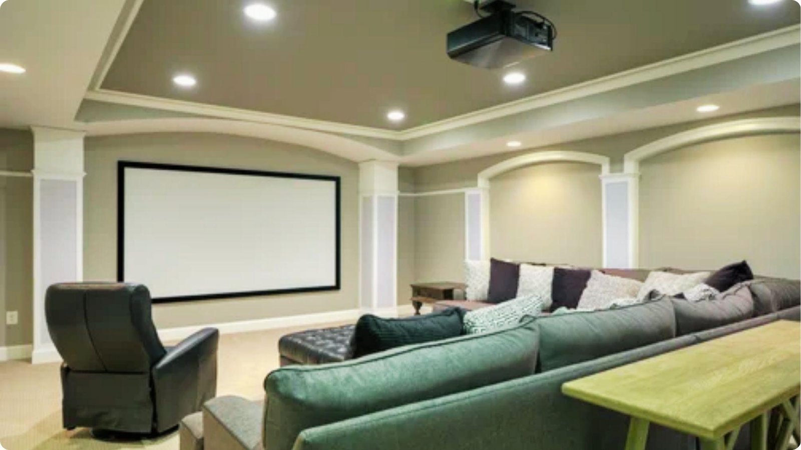 Spacious basement home theater with a large projector screen, plush sectional sofa, and recliner seating.