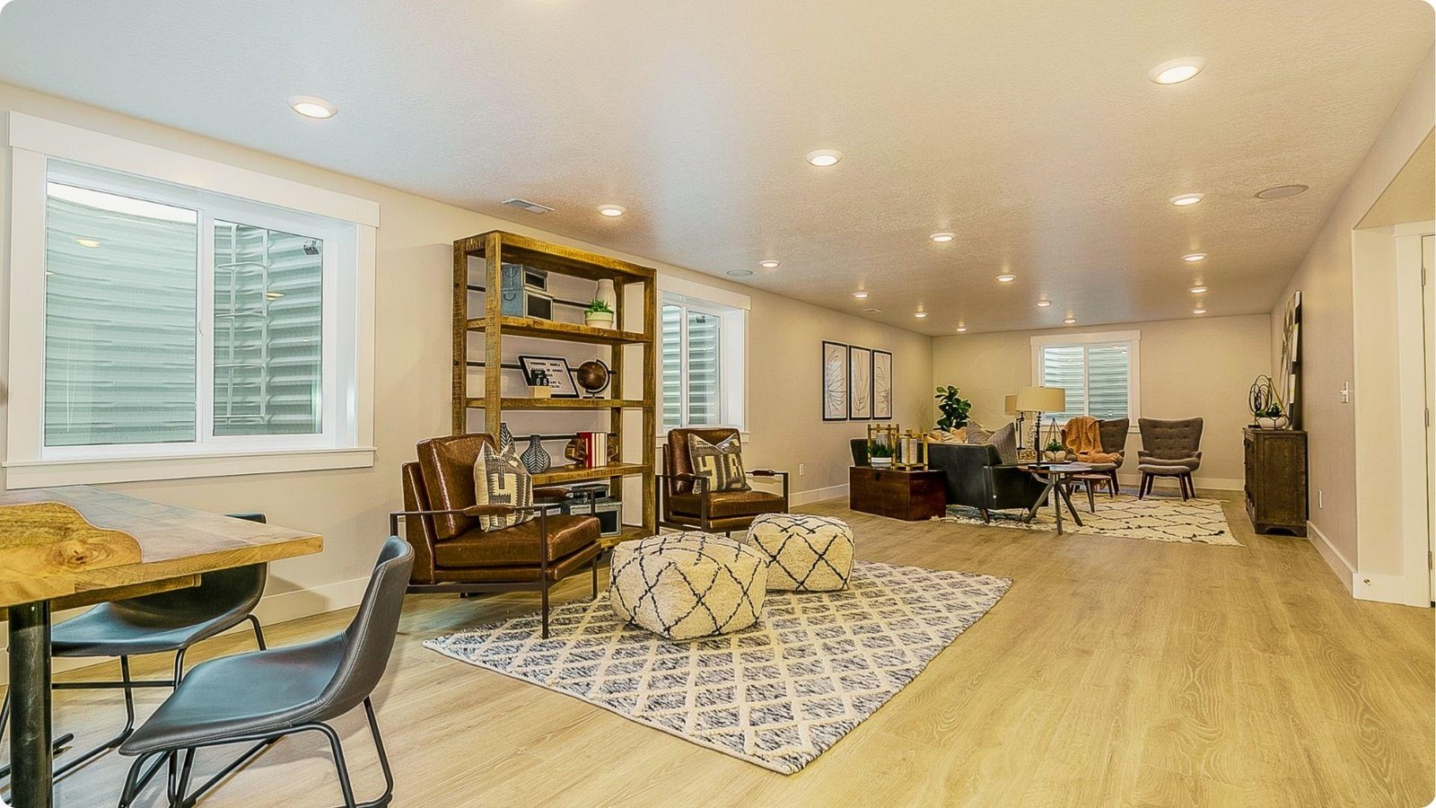 Expansive remodeled basement with wood flooring, multiple seating areas, egress windows, and recessed lighting.