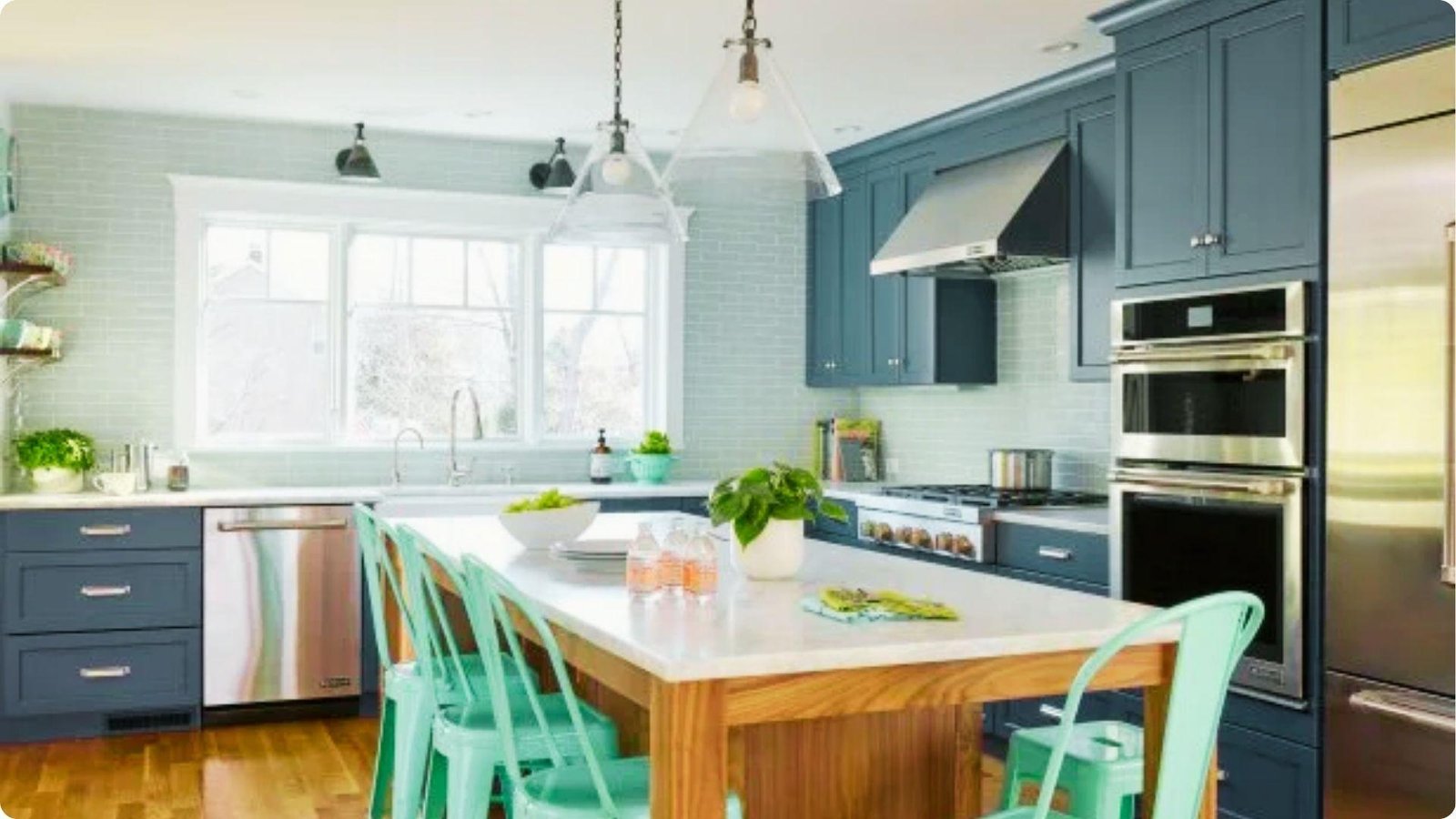 Airy basement kitchenette with navy blue cabinets, light blue subway tile, and double wall ovens.