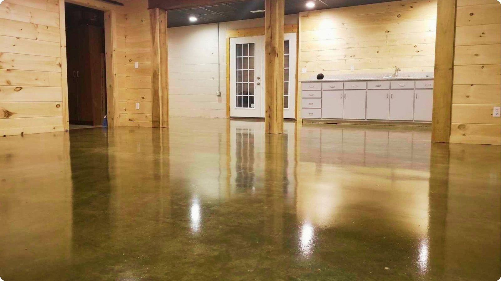 Finished basement with glossy sealed concrete floor, wood-paneled walls, and recessed lighting.