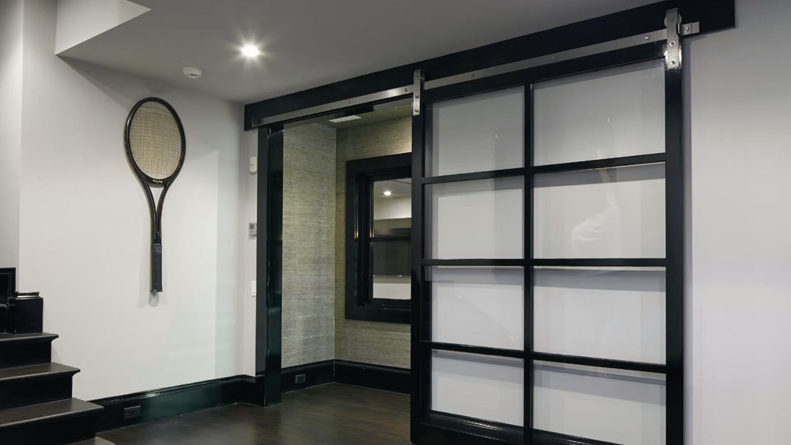 A sliding glass barn door in the basement hides a sump pump inside a utility closet with easy access.
