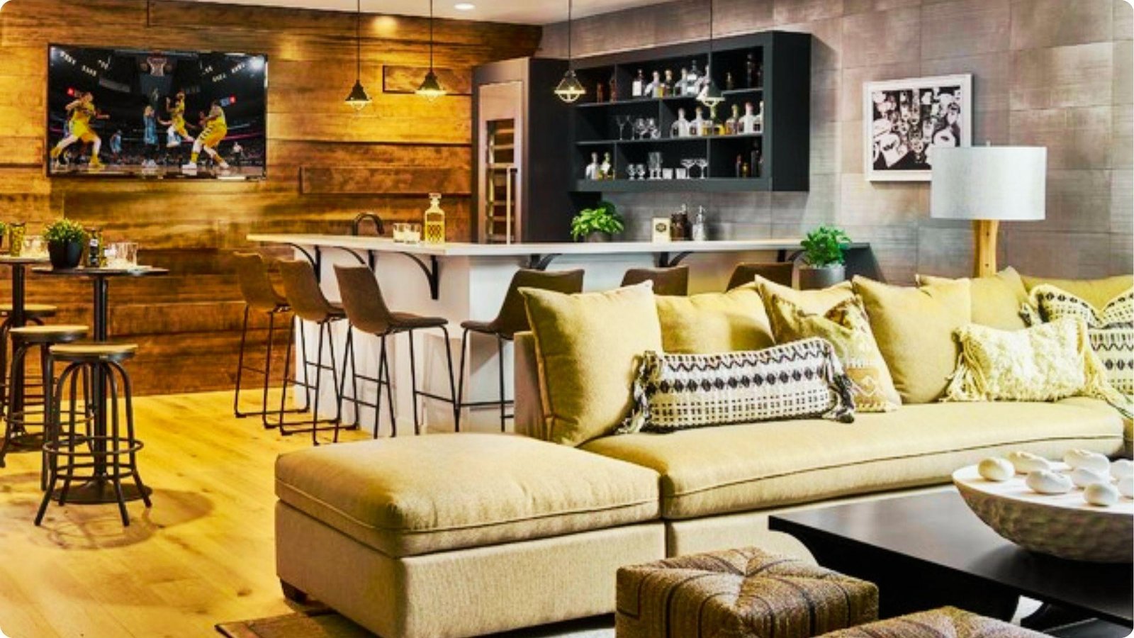 Warm basement sports bar featuring reclaimed wood walls, a large TV, and a full bar with barstool seating.