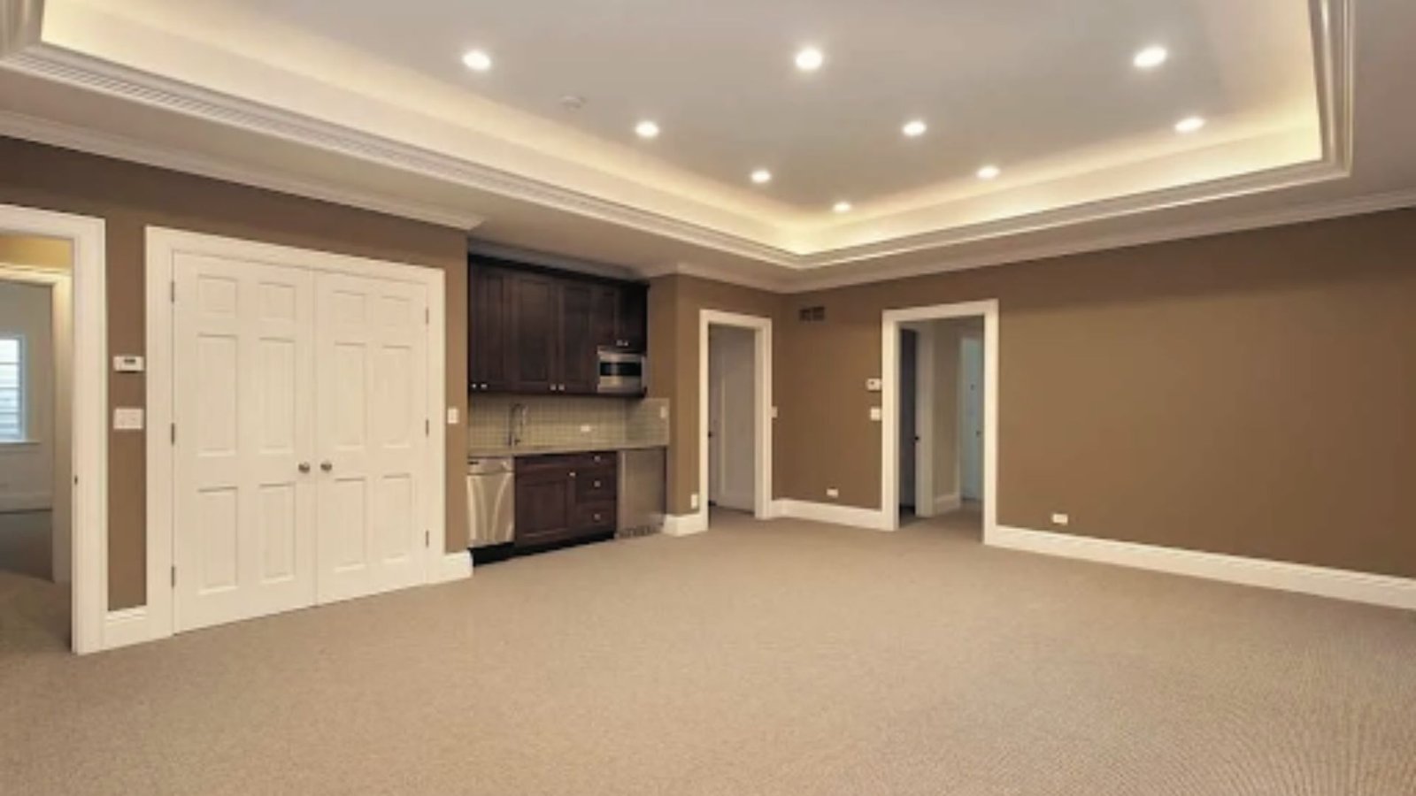 Finished basement with carpet, recessed lighting, and kitchenette showcasing full-height livable space below.