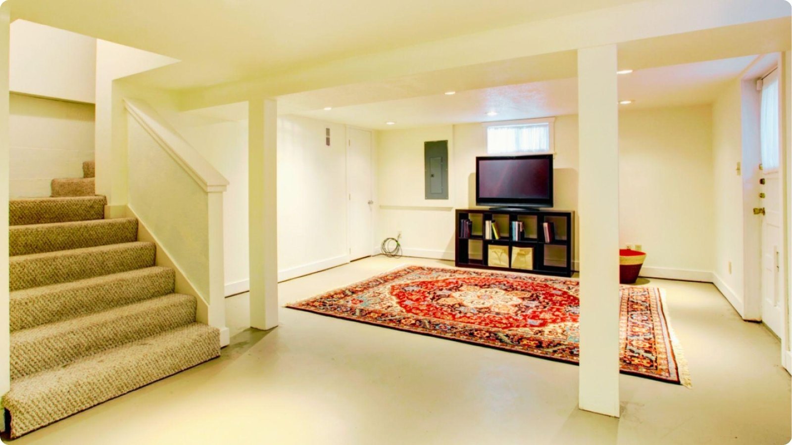 Finished basement entertainment area with concrete flooring and a large area rug.