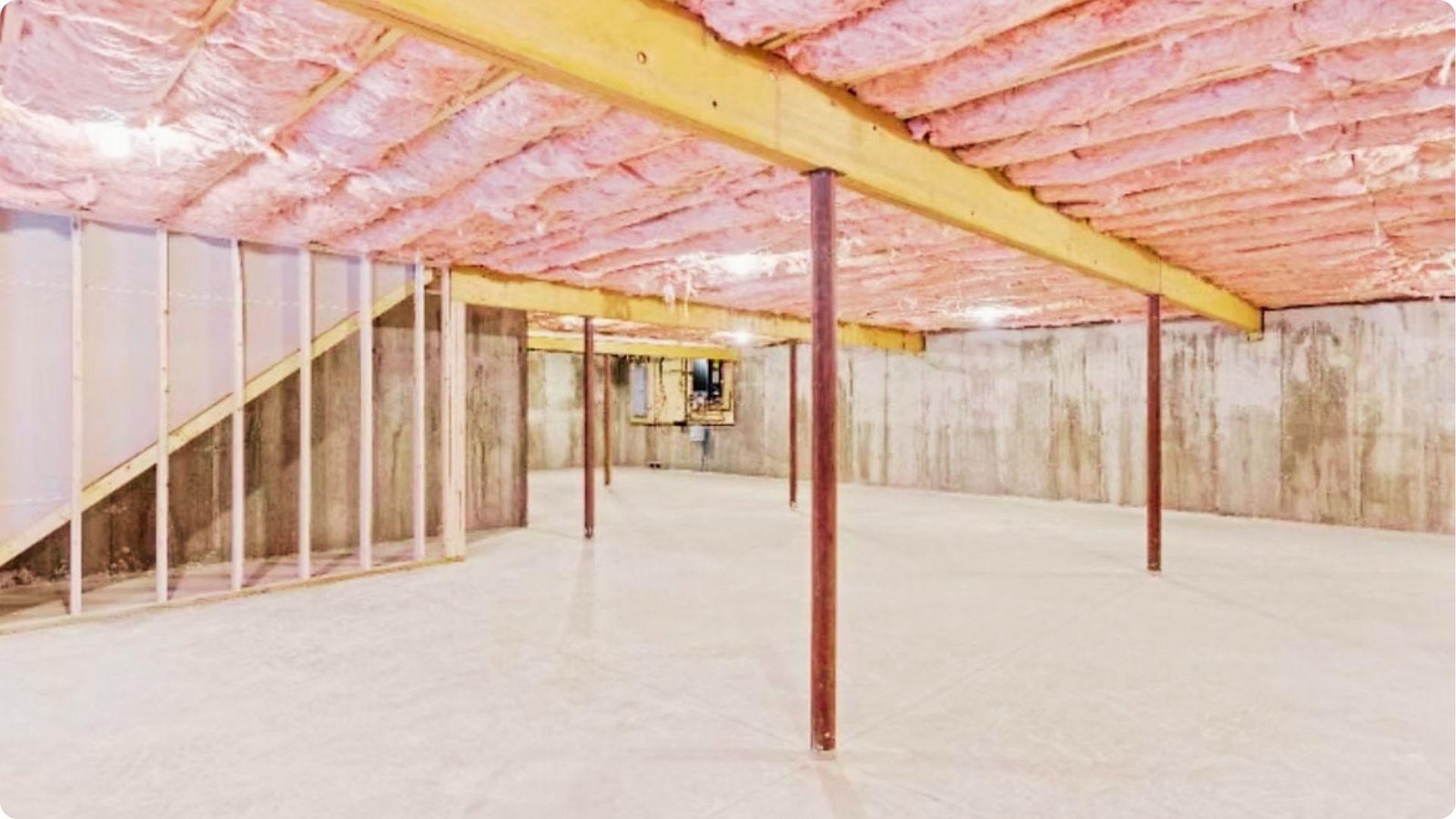 Unfinished basement with pink fiberglass batt insulation fitted between exposed ceiling joists.