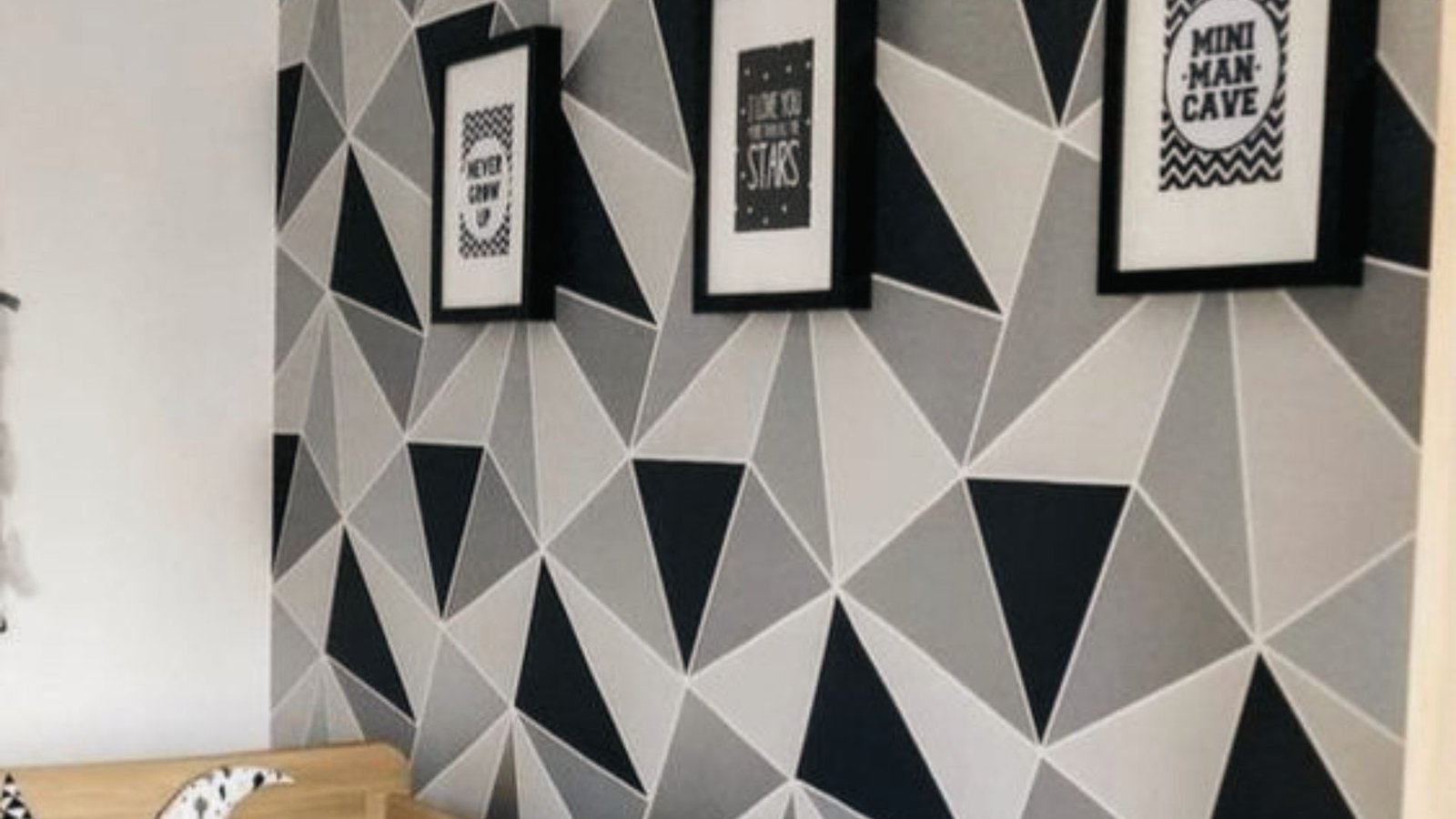Geometric wall with framed art covers sump pump access behind removable wall panel cutout.