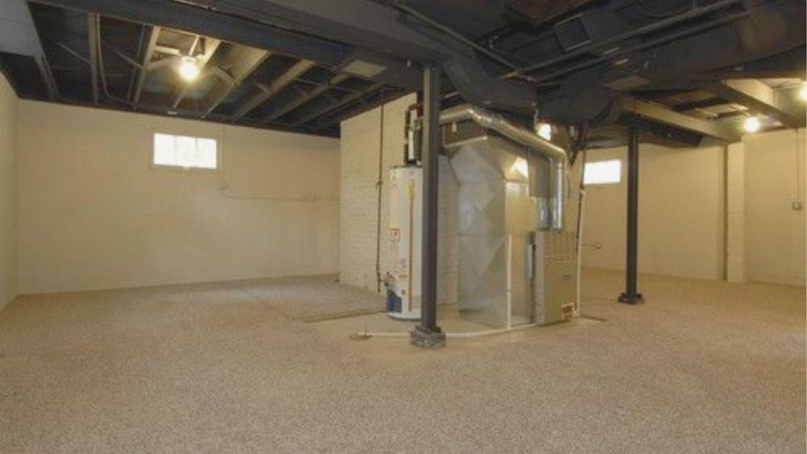 Unfinished basement space with black-painted exposed ceiling joists and ductwork contrasting against light beige walls.