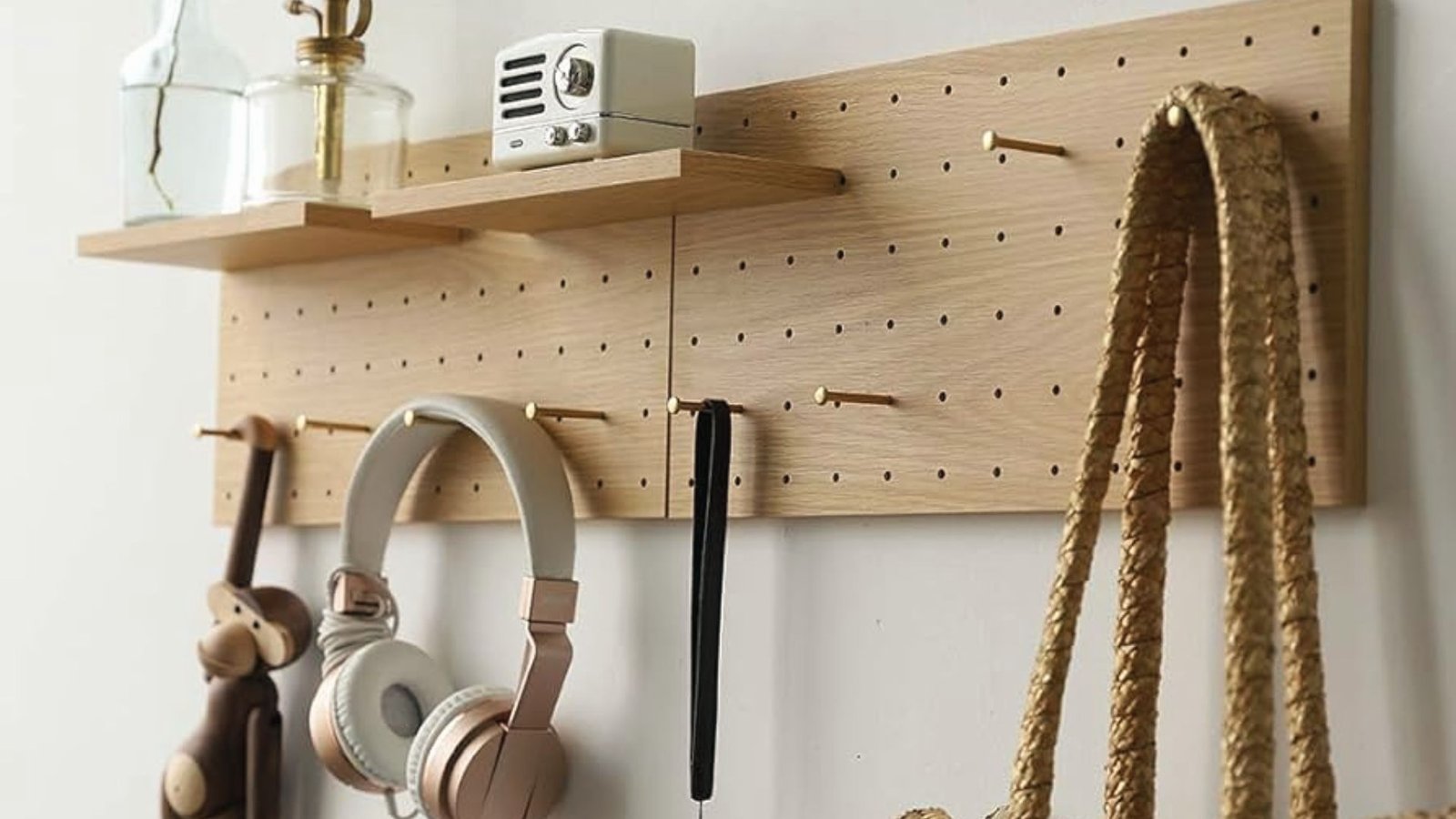 Wooden pegboard with decor and hooks hides a sump pump behind a hinged wall storage section.