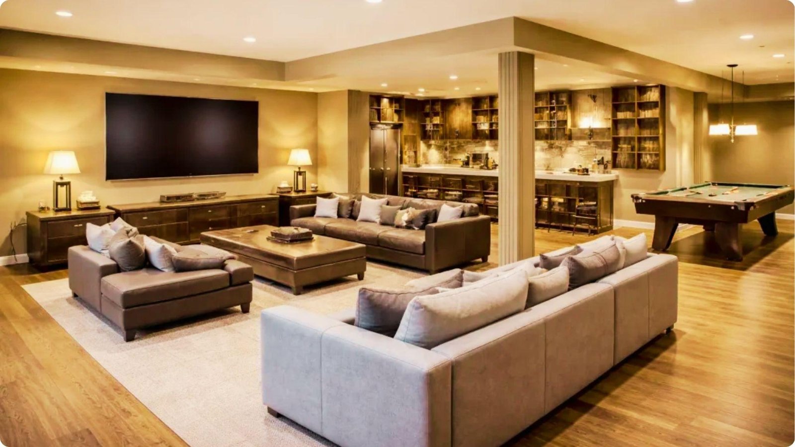 Spacious English basement entertainment room with leather sectionals, a large TV, wet bar, and pool table.