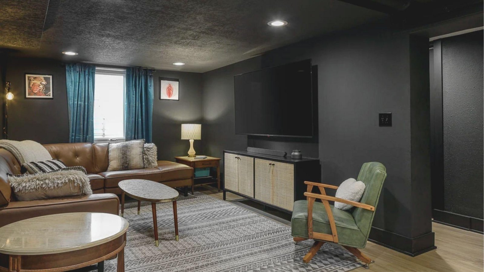 Sleek basement living room with a smooth black-painted drywall ceiling and recessed lighting over a brown leather sectional.
