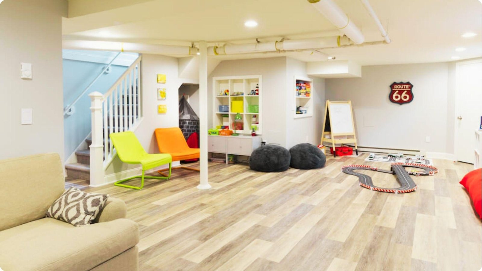 Playful basement playroom remodel with wood-look floors and colorful accent chairs.