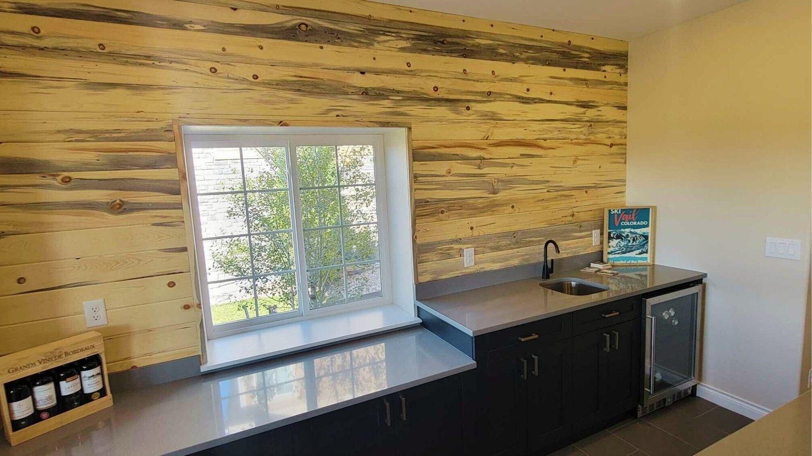 Finished basement wet bar with wood paneling adding renovation value