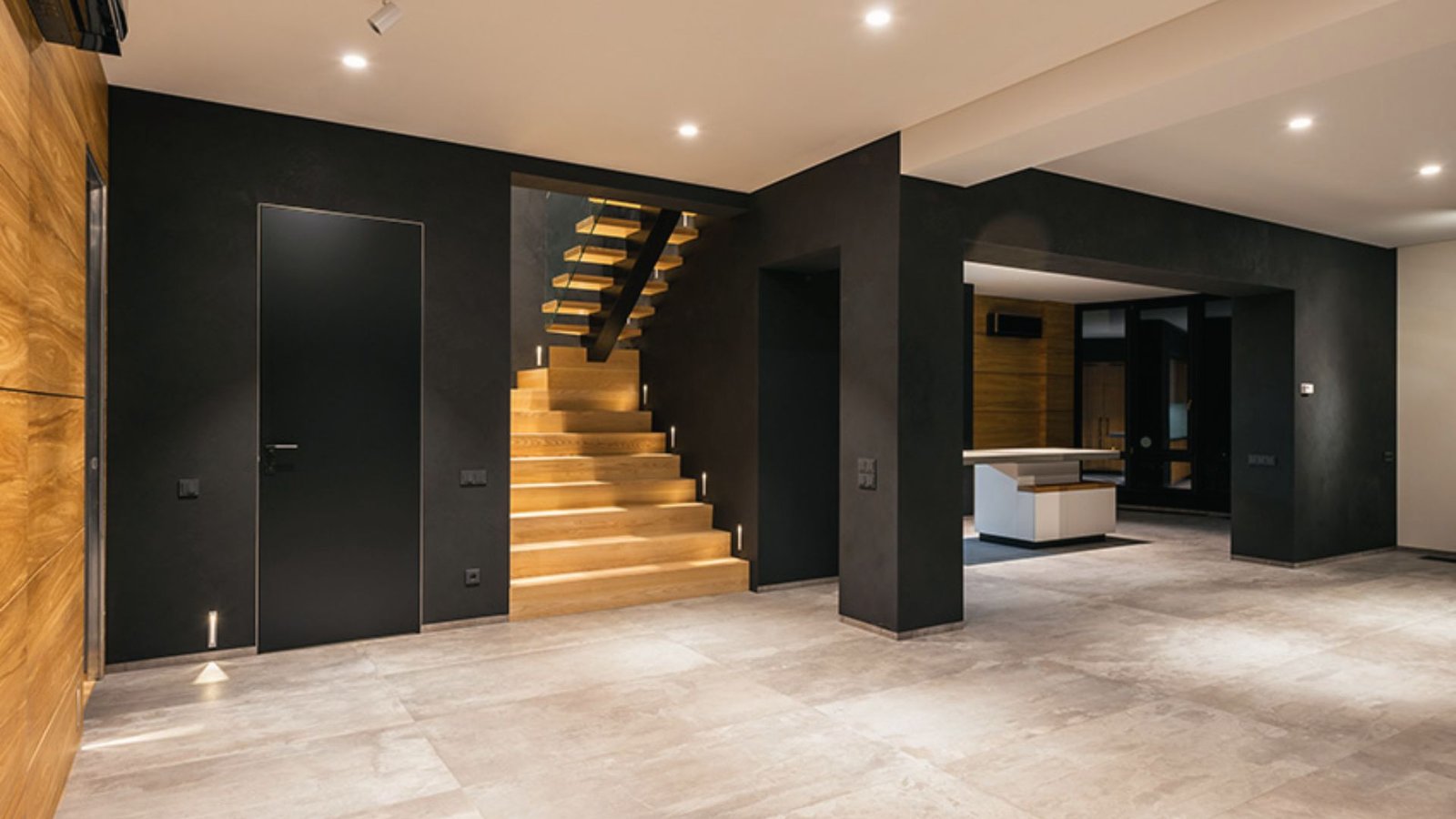 Contemporary basement with black walls, wood paneling, floating staircase and minimalist design.