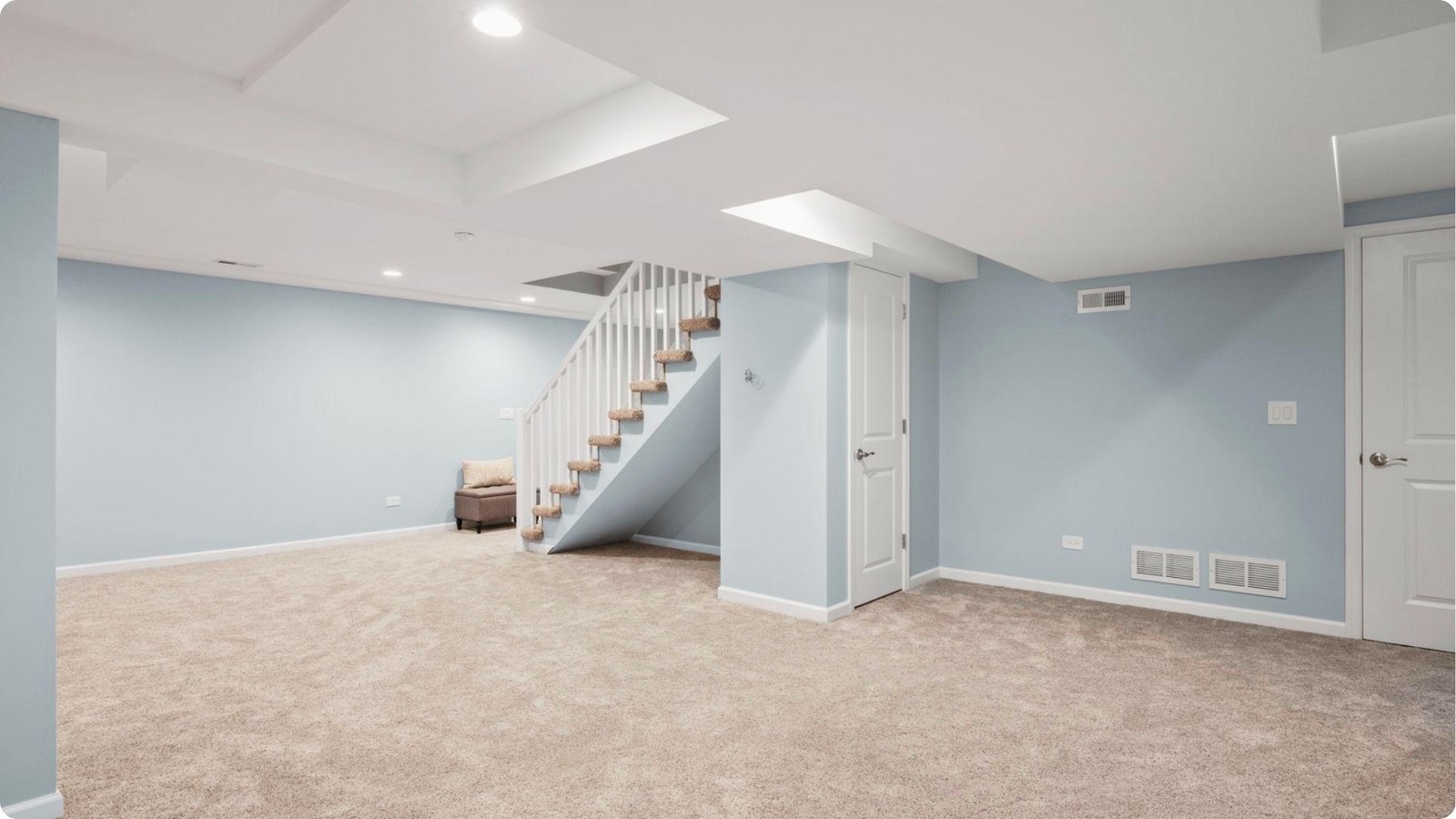 Spacious renovated basement with light blue walls and plush beige carpeting.
