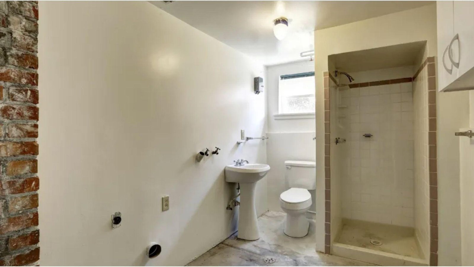 Unfinished basement bathroom with sink, toilet, and exposed plumbing